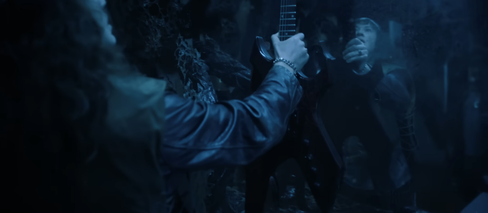 Eddie holding up a guitar in a dark room