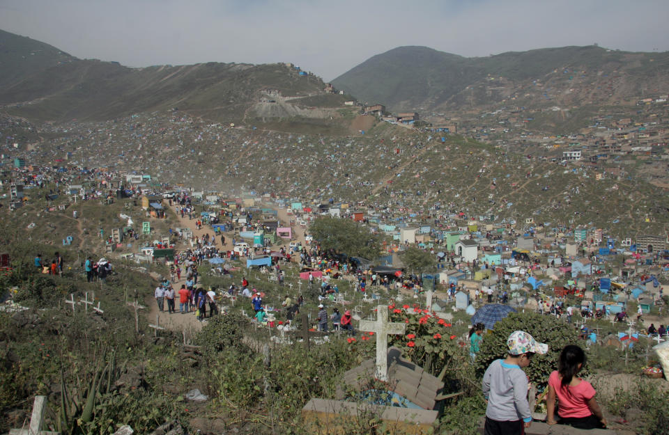 In this Nov. 1, 2012 photo, George Ramos Naveda, left, and Amin Naveda Cabrera rest on a grave overlooking the massive Cemetery of Nueva Esperanza in Villa Maria del Triunfo in Lima, Peru, during the Day of the Dead festival. (AP Photo/Jody Kurash)