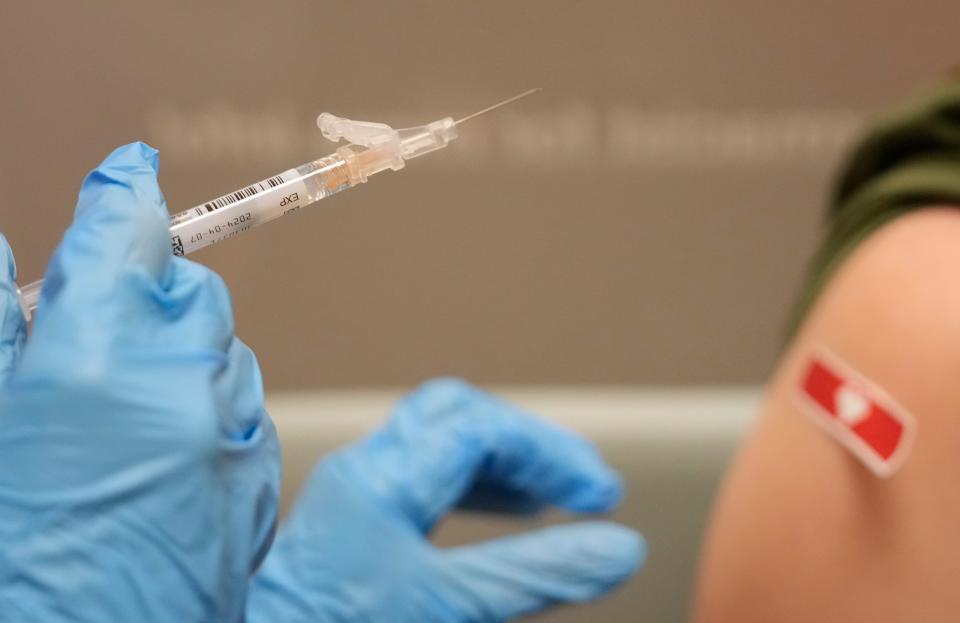 A pharmacist administers a COVID-19 shot. Pharmacists say rising workplace pressures were compounded by their pandemic duties administering COVID tests and vaccines.