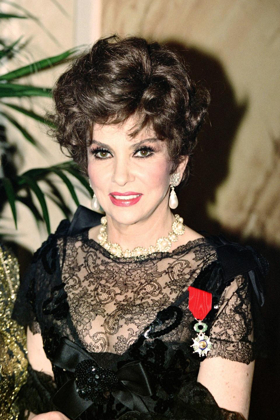 Gina Lollobrigida, honoured with the Legion of Honour, arrives with French actor Alain Delon (C), on February 17, 1993 at a reception in Paris.