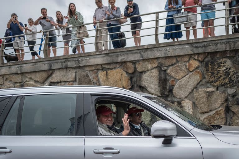 El ex rey de España Juan Carlos I saluda desde un coche en el puerto de la localidad gallega de Sanxenxo, al noroeste de España, donde asiste a la regata del trofeo InterRias de la Copa de España de 6M el 21 de mayo de 2022.