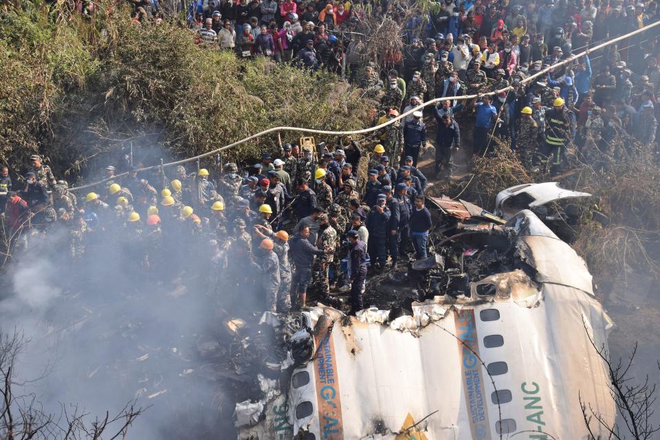 Nepalese rescue workers and civilians gather around the wreckage of a passenger plane that crashed in Pokhara, Nepal, on Jan. 15, 2023.