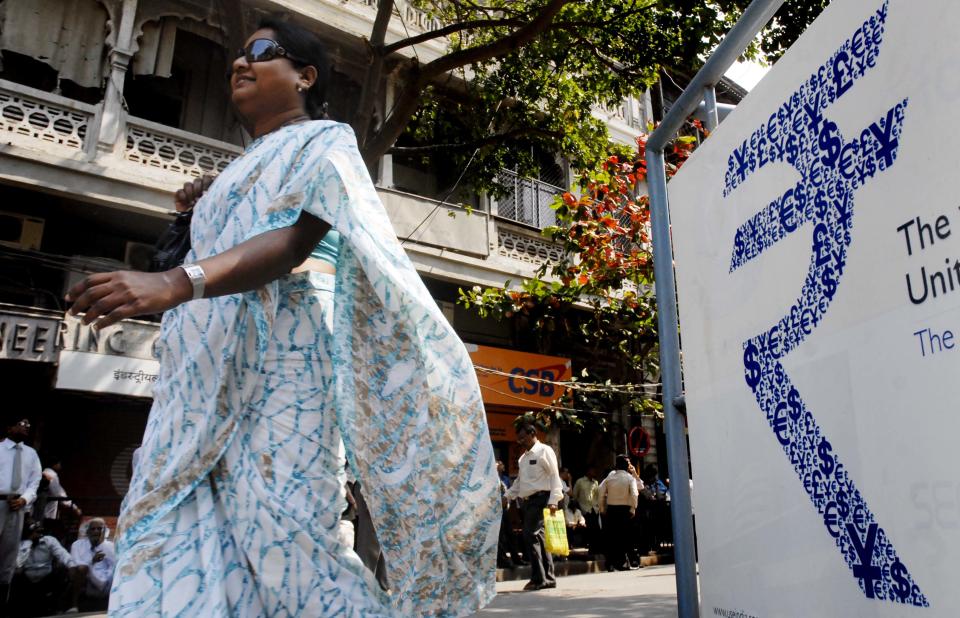 MUMBAI, INDIA - FEBRUARY 28, 2011: A Woman walks past a Rupee symbol as Budget 2011: is announced at BSE, Dalal Street Morning (Photo by Kalpak Pathak/Hindustan Times via Getty Images)