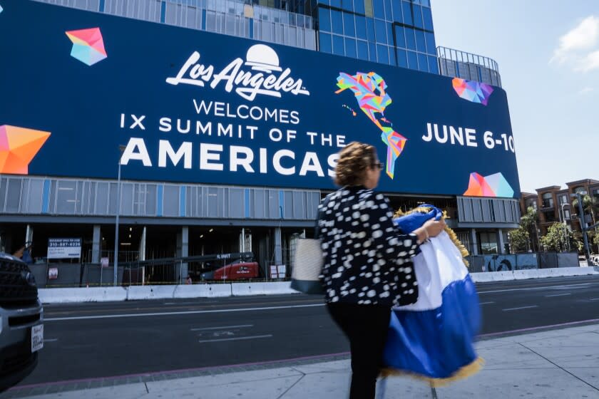 LOS ANGELES, CALIFORNIA - JUNE 06: A woman carries a Nicaraguan flag as she walks by a display advertising the Ninth Summit of the Americas on June 06, 2022 in Los Angeles, California. Leaders from North, Central and South America will travel to Los Angeles for the summit to discuss issues such as trade and migration. The United States is hosting the summit for the first time since 1994, when it took place in Miami. (Photo by Anna Moneymaker/Getty Images)