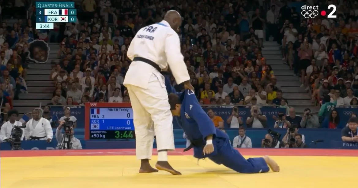 Teddy Riner soulevant littéralement son adversaire coréen de 60 kilos de moins que lui lors du quart de finale de judo à l'épreuve par équipes mixtes. (Capture d'écran France 2)