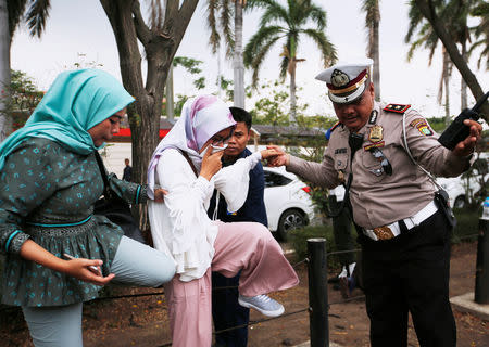 A policeman helps a woman who is a relative of a passenger of Lion Air flight JT610 that crashed into the sea, as she arrives at a crisis center at Soekarno Hatta International airport near Jakarta, Indonesia, October 29, 2018. REUTERS/Willy Kurniawan