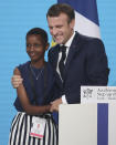 France's President Emmanuel Macron, right, poses with goodwill ambassador of the ONG "Grandir Ensemble" Amanda Dushime at the Lyon's congress hall, central France, Thursday, Oct. 10, 2019, during the meeting of international lawmakers, health leaders and people affected by HIV, Tuberculosis and malaria. Lyon is hosting the two day Global Fund event aimed at raising money to help in the global fight against the epidemics. (AP Photo/Laurent Cipriani)