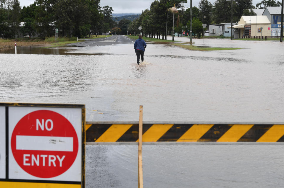 A women is seen walking through floodwaters in the town of Grantham, west of Brisbane on Thursday. Source: AAP