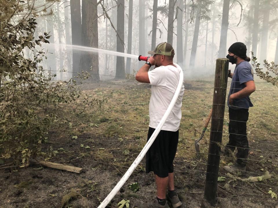 Chris Favor douses the embers of a wildfire in the Santiam Canyon area east of Salem, Ore.