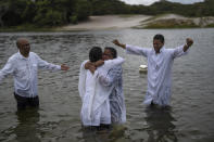 Evangelical Pastor Edy Santos, right, spreads his arms as newly baptized Zerilda Souza, center right, is embraced by a church member, in the Abaete Lagoon, in Salvador, Brazil, Sunday, Sept. 18, 2022. Santos refuses to talk politics with his flock, even when they ask. "Our country is totally divided. It's a division of thoughts," says the 32-year-old pastor. (AP Photo/Rodrigo Abd)