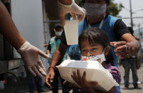 A child gets a meal from the mobile dining rooms program as people who have not been able to work because of the COVID-19 pandemic line up for a meal outside the Iztapalapa hospital in Mexico City, Wednesday, May 20, 2020. (AP Photo/Marco Ugarte)