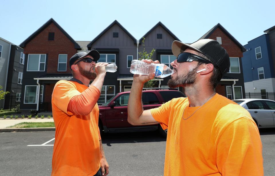 Austin Abell, right, and Justin Hunter took a water break while doing landscaping maintenance around the new housing at Beecher Terrace in Louisville, Ky. on June 14, 2022. They take a ten-minute break every hour when the temperature exceeds 90°. An excessive heat warning was issued as temperatures approached 100° on Tuesday.