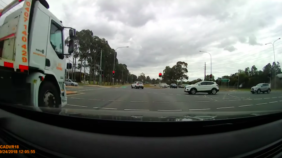 The truck passes cars waiting at the red light outside Movie World. Source: Dashcam Owners Australia/Facebook