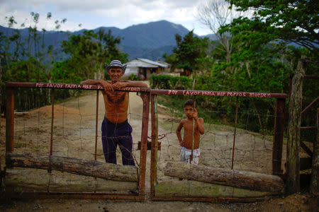 Farmer Javier Tamayo, 55, poses for a photograph with his grandson outside his home in the village of Santo Domingo, in the Sierra Maestra, Cuba, 22March 31, 2018. REUTERS/Alexandre Meneghini