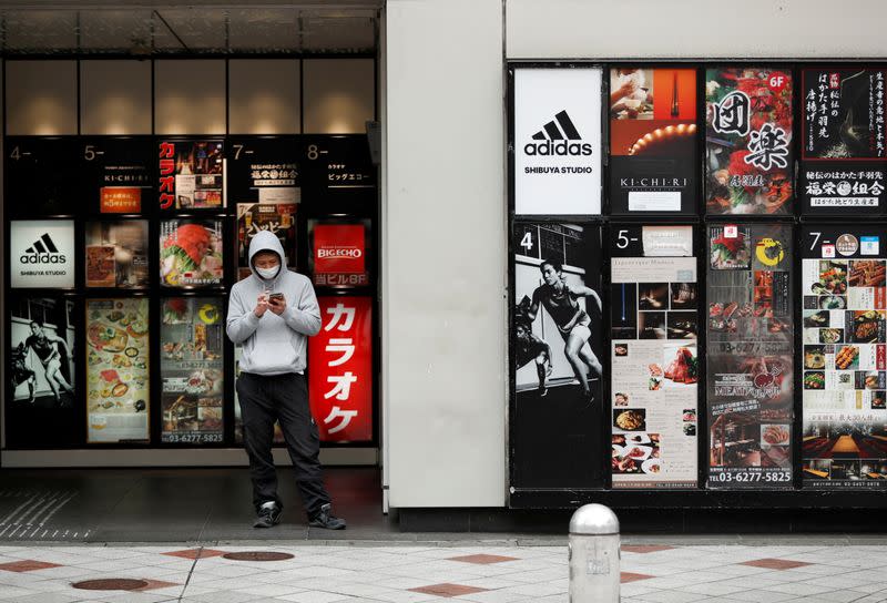 A man wearing a protective face mask, following an outbreak of the coronavirus disease, uses a cellphone at the entrance of amusements, restaurants and shopping building complex at Shibuya district in Tokyo