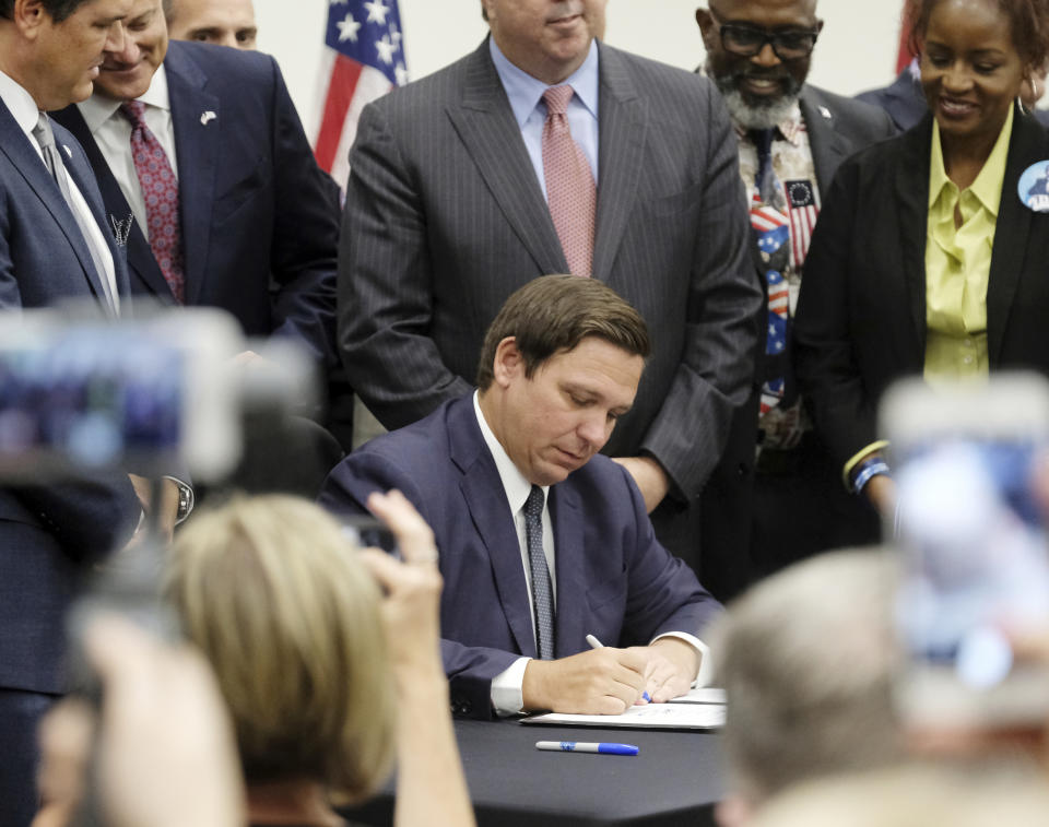 Florida Gov. Ron DeSantis signs the Sanctuary City bill Friday, June 14, 2019 at the Okaloosa County, Fla., Commission Chambers in Shalimar Fla. The bill requires all law enforcement agencies in Florida to cooperate with federal immigration authorities. (Michael Snyder/Northwest Florida Daily News via AP)