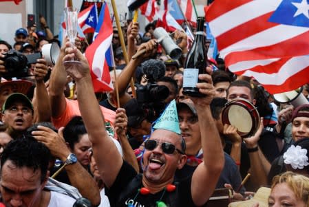 Demonstrators chant, wave Puerto Rican flags, and drink champagne celebrating the official resignation of now ex-governor of Puerto Rico Ricardo Rossello, in San Juan