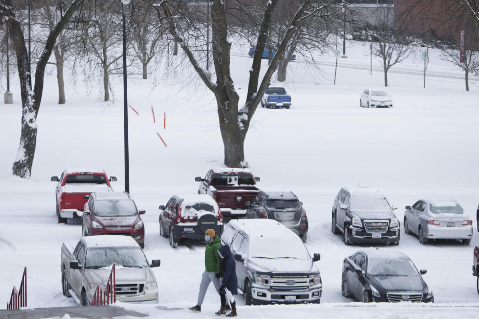 Pedestrians walk on the the Washington State University campus as light snow falls in Pullman, Wash., Saturday, Feb. 13, 2021. (AP Photo/Young Kwak)