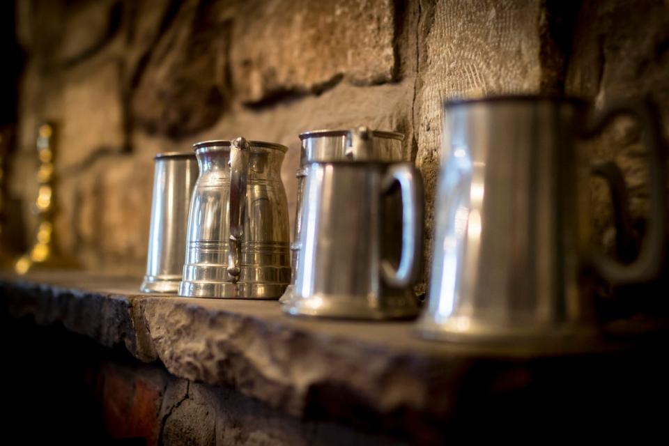 Traditional polished pewter tankard in a pub, on a stone ledge.