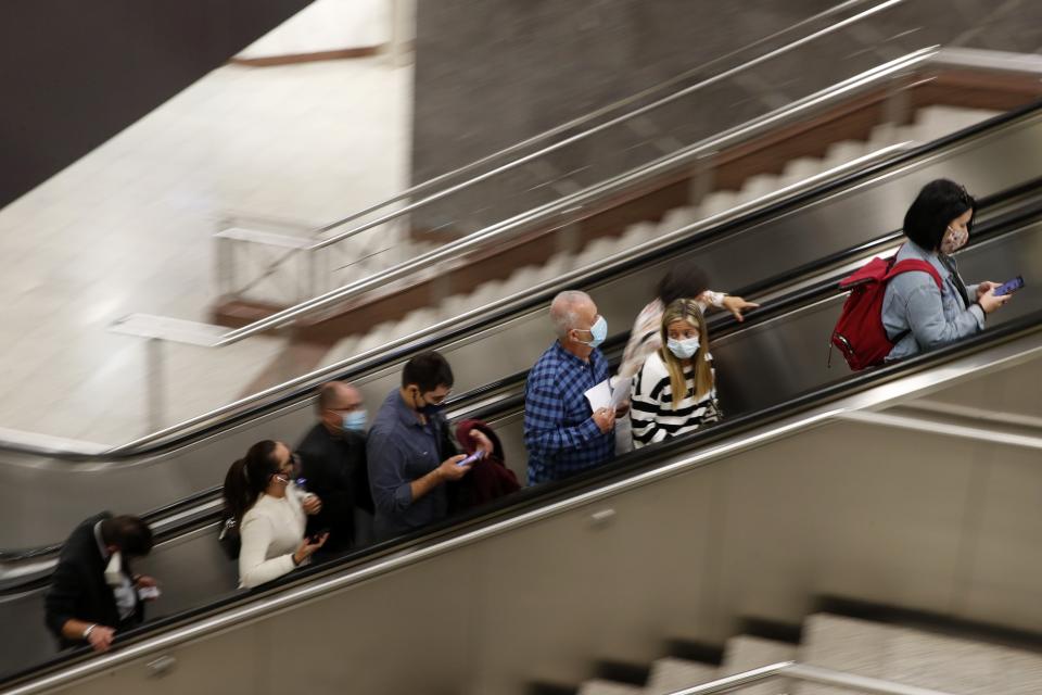 Commuters wearing face masks to curb the spread of COVID-19 use the escalator at Syntagma station, the busiest metro station, in central Athens, Tuesday, Oct. 20, 2020. Greece has been experiencing a resurgence of the virus, with the number of new daily cases, most in the Greek capital, often topping 400, and both deaths and the number of those in intensive care units rising. (AP Photo/Thanassis Stavrakis)