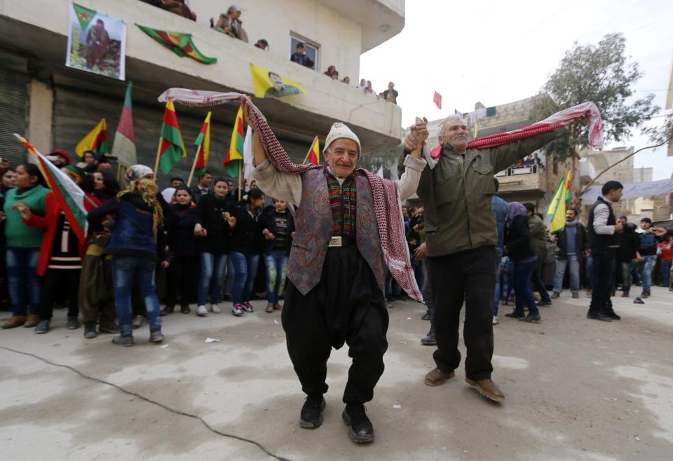 Kurdish civilians perform a traditional dance as they celebrate, after reports of Kurdish forces taking control of the Syrian town of Kobani, in Aleppo