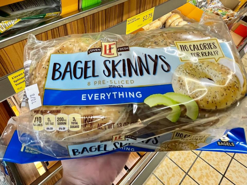 Hand holding blue and clear package of Aldi bagel things