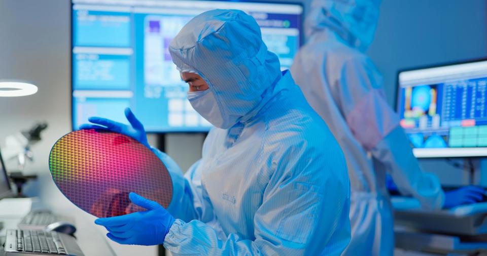 Technician holds up a semiconductor wafer. 