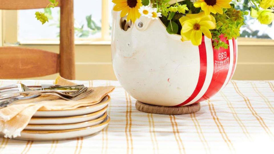 flowers arranged in a vintage football hemut infront of a window with blue sky