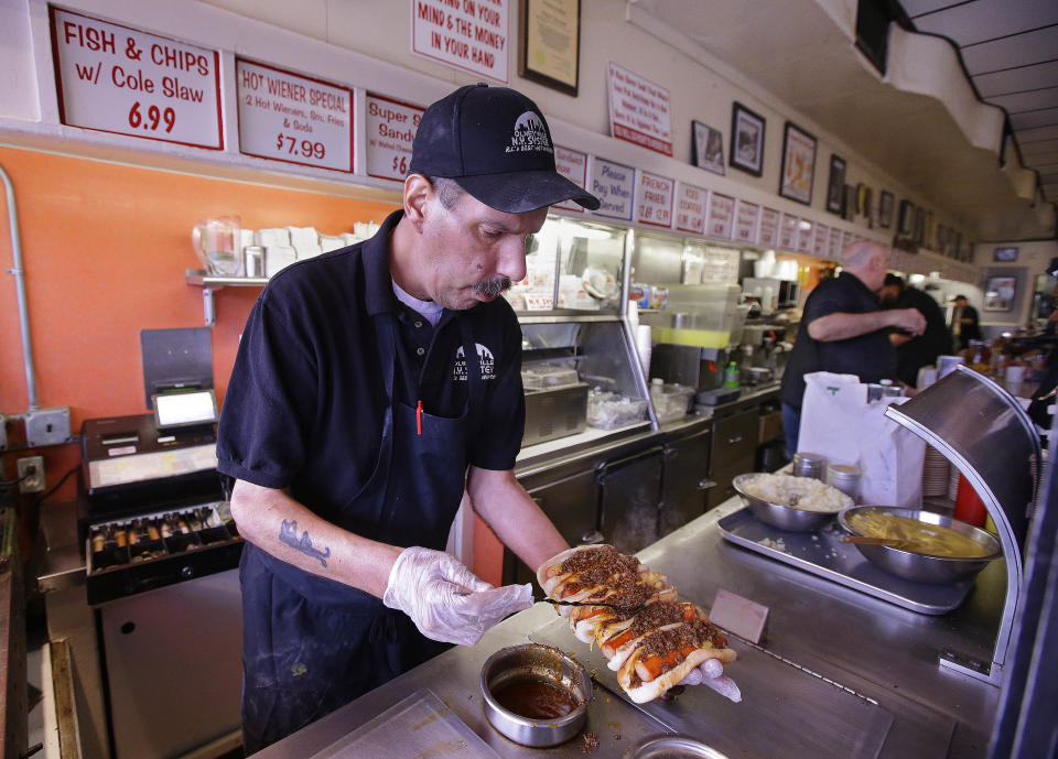 In this Monday, March 3, 2014 photo Sal O'Brien holds wieners he preps "all the way" for a customer's order at Olneyville New York System of Providence in Providence, R.I. The James Beard Foundation named the Rhode Island restaurant one of five "American Classics". (AP Photo/Stephan Savoia)