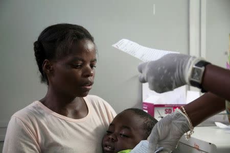 A mother holds her son suffering from yellow fever as she waits for a prescription at a hospital in Luanda?, Angola, March 15, 2016. REUTERS/Herculano Coroado
