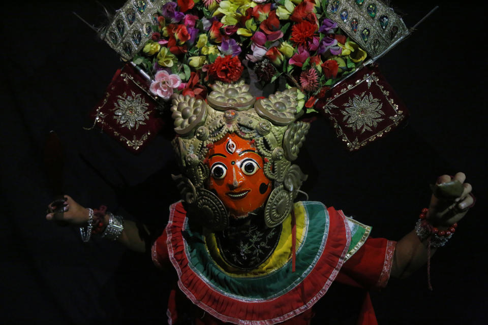 In this Sept. 23, 2018, photo, a dancer poses for photographs wearing goddess Kumari mask in Kathmandu, Nepal. For centuries, Nepal has celebrated the Indra Jatra festival of masked dancers, which officially begins the month-long festivities in the Hindu-dominated Himalyan nation. The dancers, who come from a variety of backgrounds, pull off this performance every year despite minimal financial support from the government and other sources, they say. (AP Photo/Niranjan Shrestha)