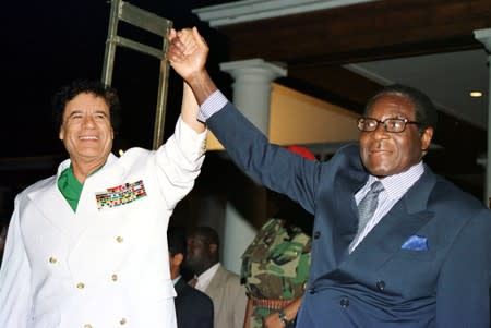 FILE PHOTO: Libyan leader Colonel Muammar Gaddafi (L) and Zimbabwe President Robert Mugabe greet supporters outside State House in Harare, Zimbabwe