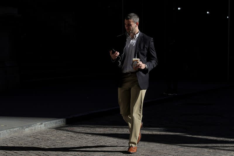 A man uses his phone on Wall St. outside the NYSE in New York