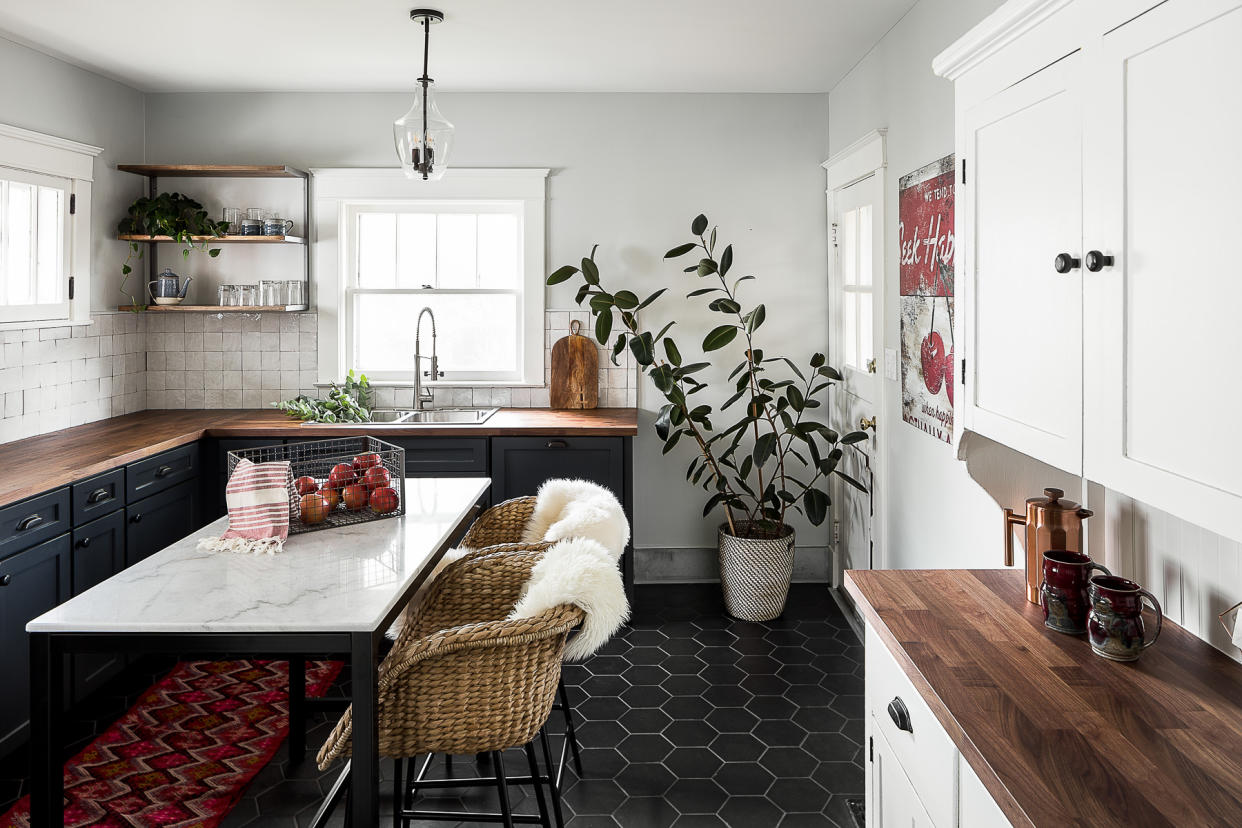  A kitchen with dark flooring and white walls, with a marble island. 