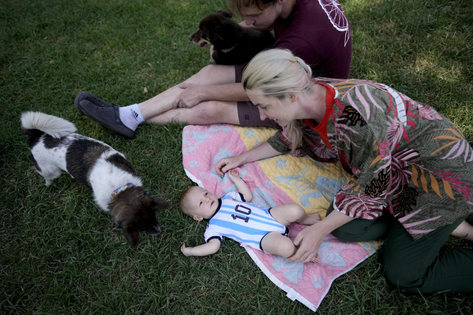 Russian nationals Alla Prigolovkina and her husband Andrei Ushakov, their Argentine-born son Lev Andres and their dogs Santa and Cometa, visit a park in Mendoza, Argentina, Tuesday, Feb. 14, 2023. In spite of the language barrier and the stifling summer heat, Prigolovkina and Ushakov have quickly adopted Argentine customs since their July move. Prigolovkina said they especially enjoy spending time in the park with their dogs. (AP Photo/Natacha Pisarenko)