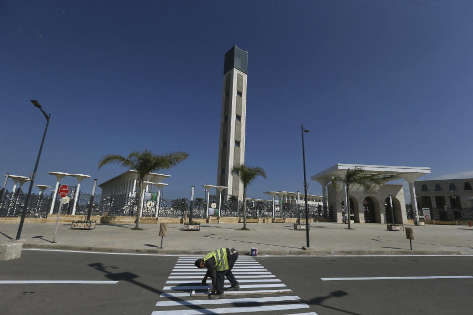 A worker paints the road outside the Djamaa El-Djazair, or Algiers Great Mosque, Wednesday, Feb.21, 2024 in Algiers. Begun in 2012, the Great Mosque of Algiers boasts a giant 265 meter (290 yard) minaret and a capacity for 120,000 faithful.(AP Photo/Anis Belghoul)