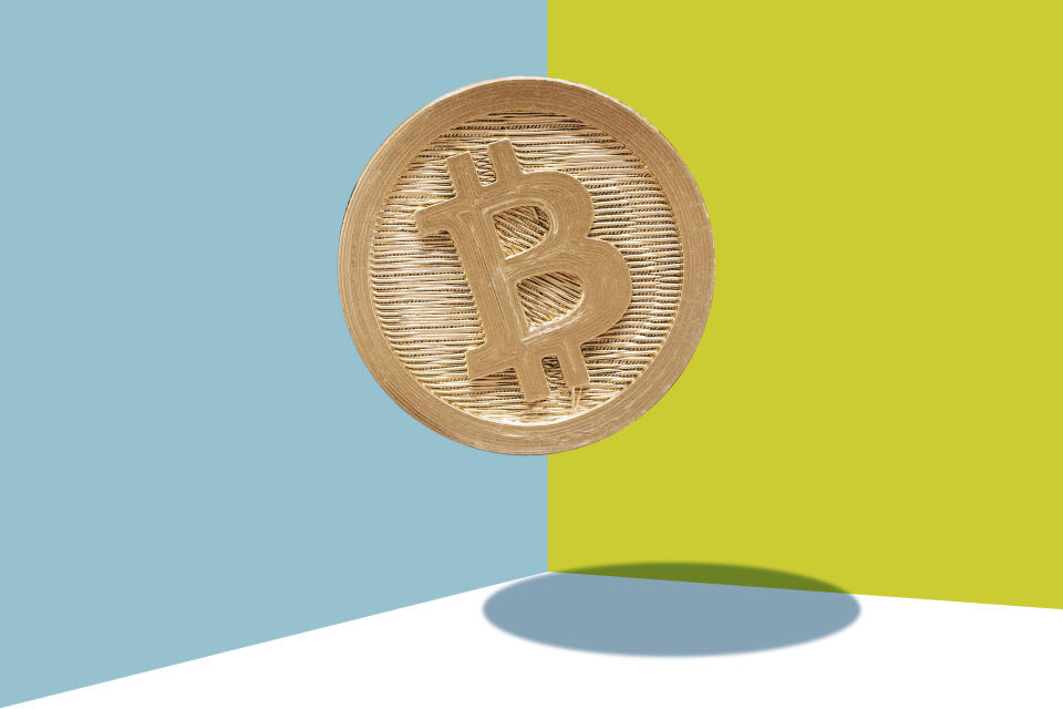 Gold Bitcoin Suspended on a blue and yellow background.