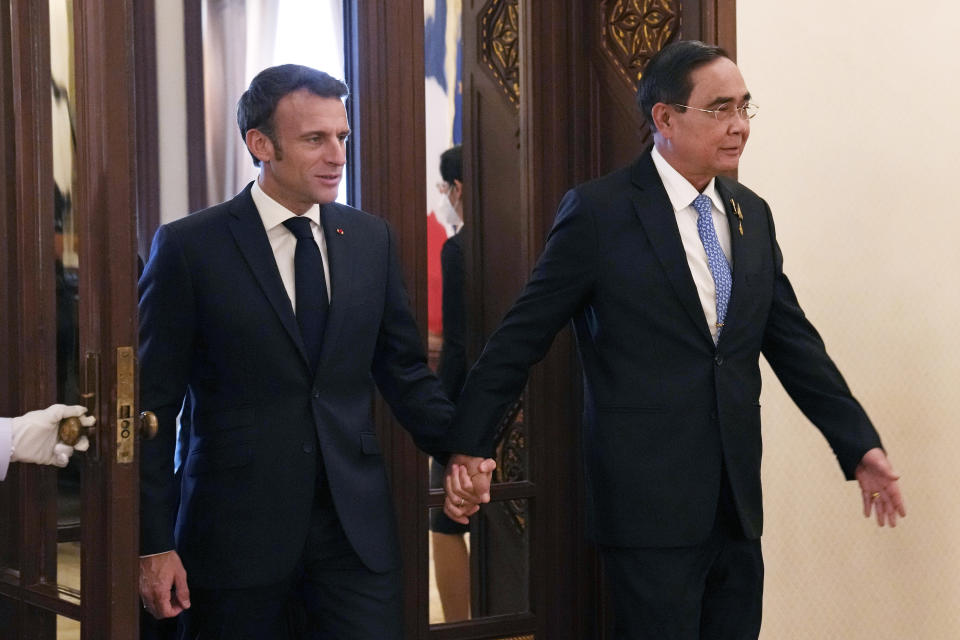 Thailand's Prime Minister Prayuth Chan-ocha, right, walks hand in hand with French President Emmanuel Macron before their meeting at the Government House, Thursday, Nov. 17, 2022, in Bangkok, Thailand. (AP Photo/Sakchai Lalit, Pool)