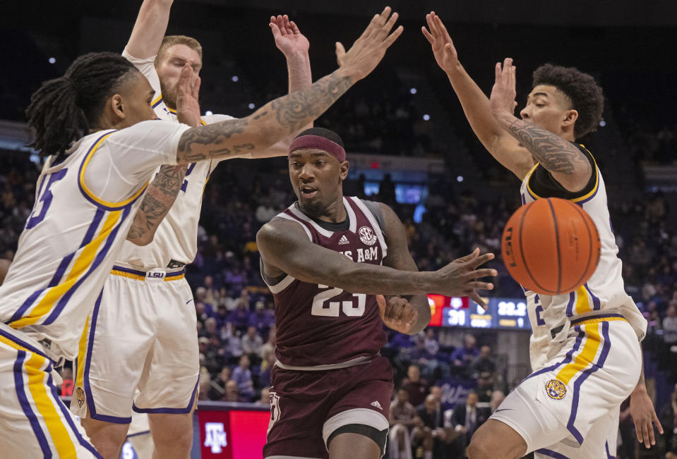 Texas A&M guard Tyrece Radford (23) passes the ball around LSU forwards Tyrell Ward, front left, Hunter Dean, back left, and Jalen Reed, right, under the basket during an NCAA college basketball game Saturday, Jan. 20, 2024, in Baton Rouge, La. (Hilary Scheinuk/The Advocate via AP)