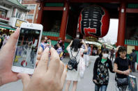 <p>A man tries to catch a Pikachu, a Pokemon character, while he plays “Pokemon Go” in front of Kaminarimon, or Thunder Gate, at the Sensoji temple in Tokyo’s Asakusa shopping and tourist district, Friday, July 22, 2016. The wait is over for “Pokemon Go” fans in Japan. Players began tweeting about it as soon as it was available Friday morning, and the Pokemon Co. and the developer of the augmented reality game, U.S.-based Niantic Inc., confirmed its launch. (AP Photo/Eugene Hoshiko)</p>