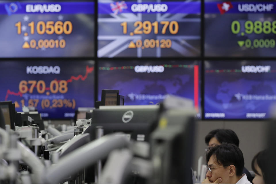 A currency trader watches computer monitors near screens showing the foreign exchange rates at the foreign exchange dealing room in Seoul, South Korea, Monday, Nov. 18, 2019. Asian shares are mixed Monday in a cautious mode after Wall Street closed out the week with milestones as the Dow Jones Industrial Average crossed 28,000 for the first time and the S&P 500 and Nasdaq hit record highs. (AP Photo/Lee Jin-man)