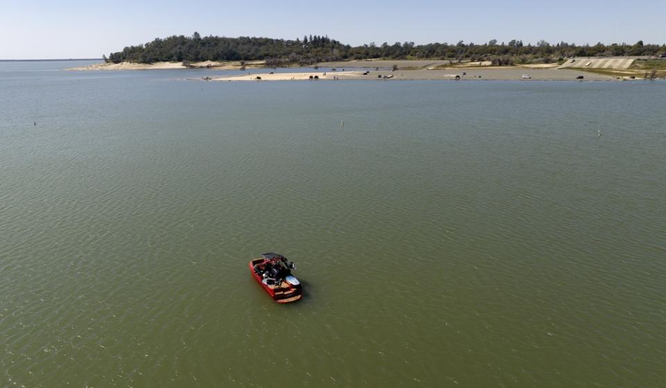 In an aerial view, a boat floats in the Granite Bay area of Folsom Lake, in Granite Bay, Calif., on Sunday, March 26, 2023. Months of winter storms have replenished California’s key reservoirs after three years of punishing drought. (AP Photo/Josh Edelson)