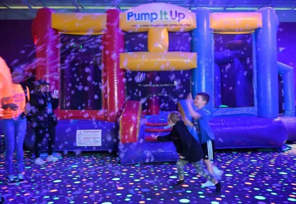 Niños persiguen burbujas en una experiencia que brilla en la oscuridad en Pump It Up un sábado reciente.