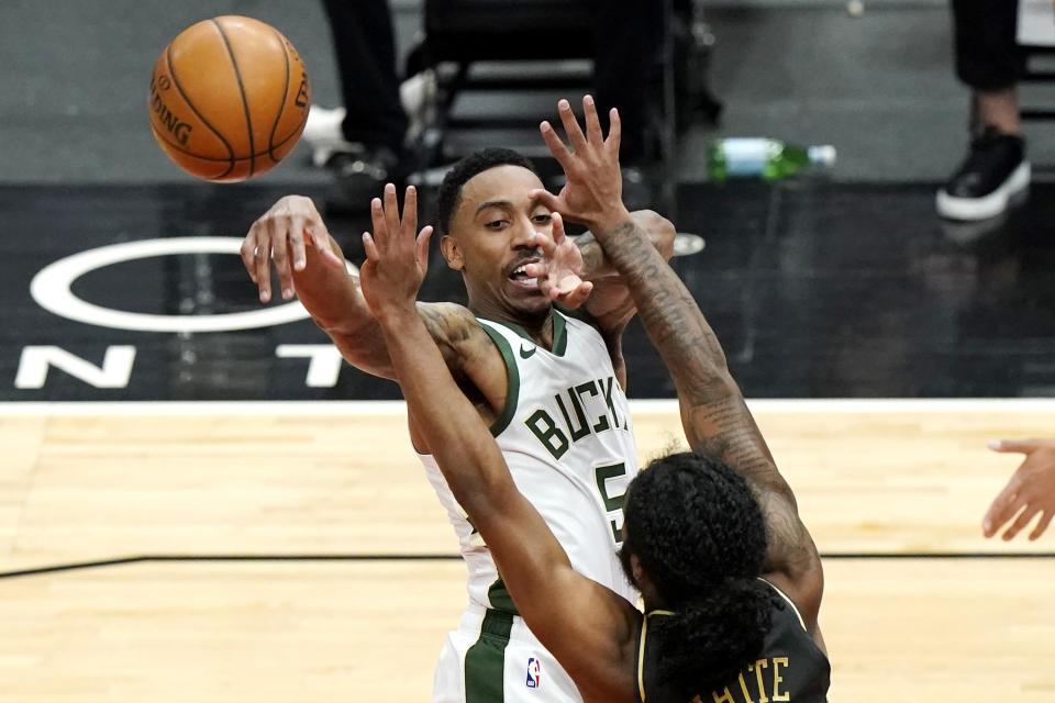 Milwaukee Bucks guard Jeff Teague, top, passes the ball against Chicago Bulls guard Coby White during the first half of an NBA basketball game in Chicago, Friday, April 30, 2021. (AP Photo/Nam Y. Huh)