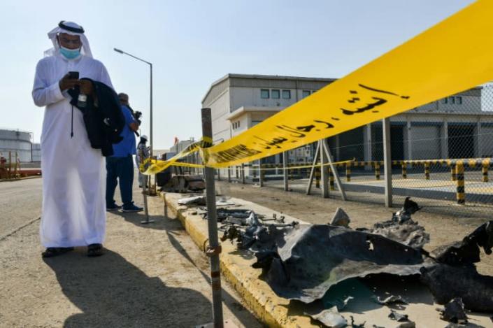 A man checks his phone while standing near debris following an attack at the Saudi Aramco oil facility in Saudi Arabia's Red Sea city of Jeddah on November 24, 2020