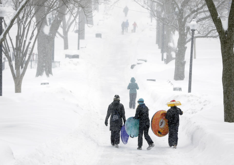 FILE - People carry their sleds along a snow-covered walkway in the Boston Common, Monday, Feb. 9, 2015, in Boston. For much of the Eastern United States, the winter of 2023 has been a bust. Snow totals are far below average from Boston to Philadelphia in 2023 and warmer temperatures have often resulted in more spring-like days than blizzard-like conditions. (AP Photo/Steven Senne, File)