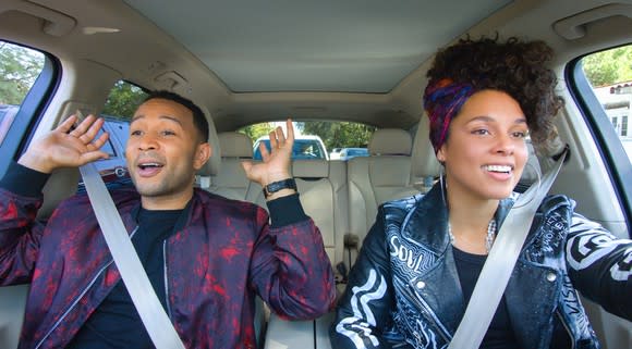 A scene from an episode of "Carpool Karaoke" featuring John Legend and Alicia Keys singing in a car.