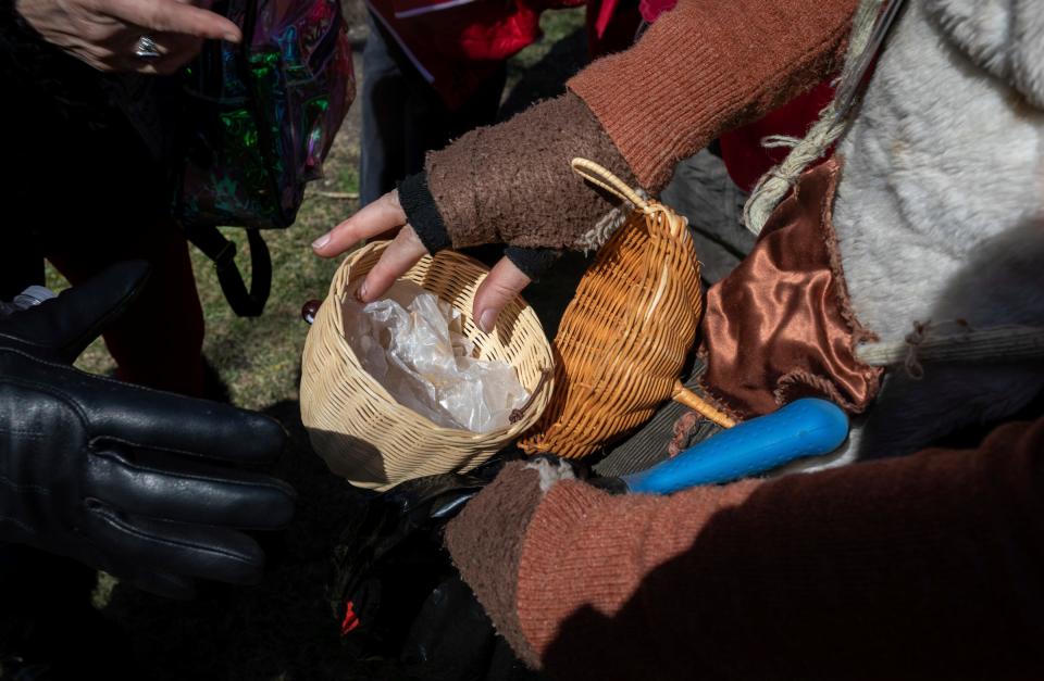 Lynn Blasey, 40, program manager of the Community Arts Partnerships office at the College for Creative Studies, looks through her acorn shaped bag during the Marche du Nain Rouge 2024 parade in Detroit on Sunday, March 24, 2024.