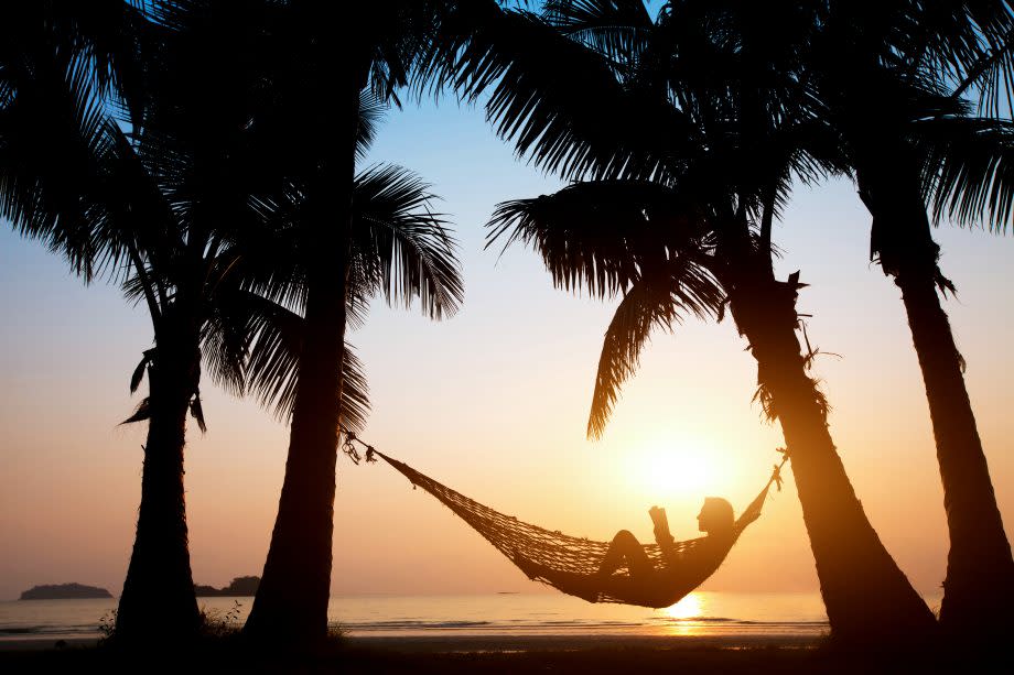 Bitcoin-Trader in Hängematte am Strand unter Palmen.