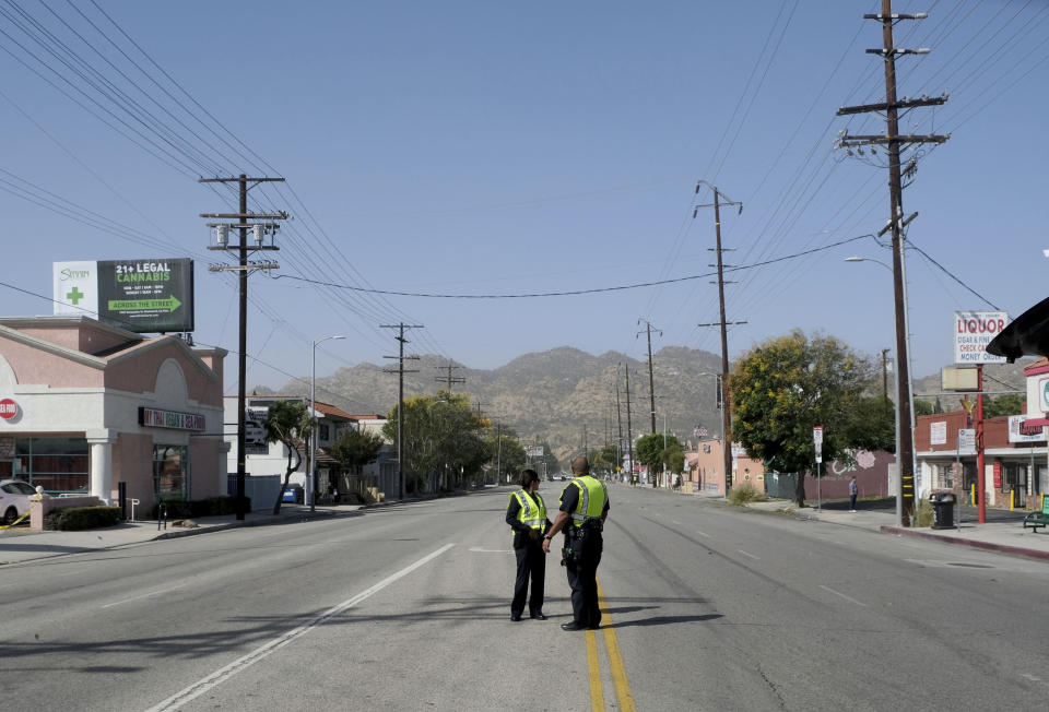 Strong Santa Ana winds in Chatsworth, CA., blew across power lines causing them to arc and transformers to explode. Power was out for street signs, businesses and residents. Two LAPD officers stand on a closed Devonshire St. at Owensmouth Ave., east of Topanga Canyon Blvd. on Thursday, Oct. 10, 2019. (Dean Musgrove/The Orange County Register via AP)